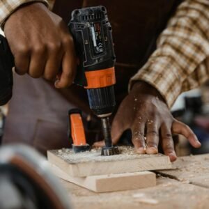 A craftsman skillfully uses a drill on a wooden board, showcasing woodworking precision.
